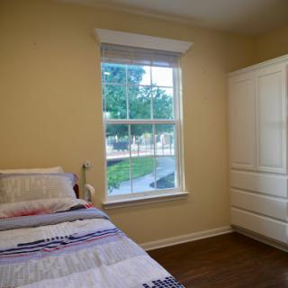 A cozy bedroom featuring a neatly made bed, a dresser, and a window that lets in natural light.