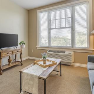 A cozy living room with a television, coffee table, and large window allowing natural light.