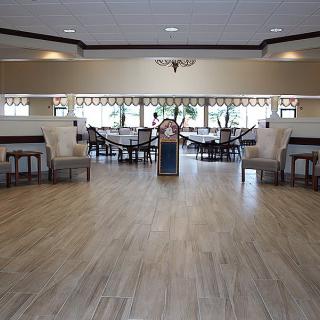 An empty dining area with wooden flooring and neatly arranged tables and chairs.