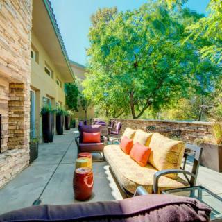 A sunny outdoor patio with comfortable seating and lush greenery.