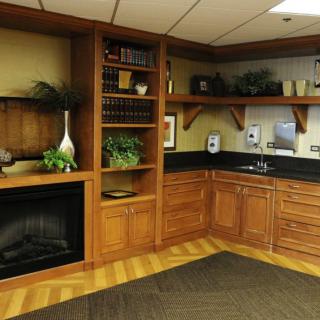 A cozy office corner featuring a wooden bookshelf, built-in fireplace, and cabinetry with a small sink.