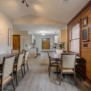 A modern dining area with a view into the kitchen, featuring sleek furniture and warm lighting.