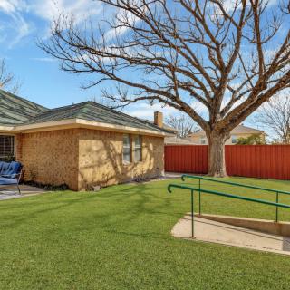 A single-story brick house with a large tree in the yard and a ramp leading to the entrance.