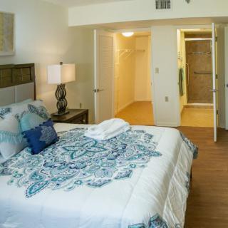 A cozy bedroom with a neatly made bed, decorative pillows, and an open door leading to a walk-in closet.
