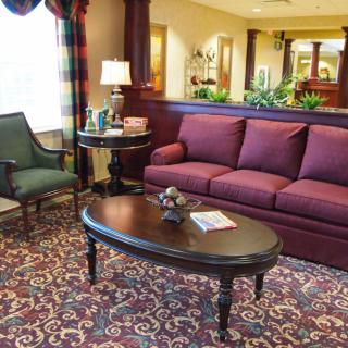 A cozy living room with a burgundy sofa, armchair, and a dark wooden coffee table on a patterned carpet.