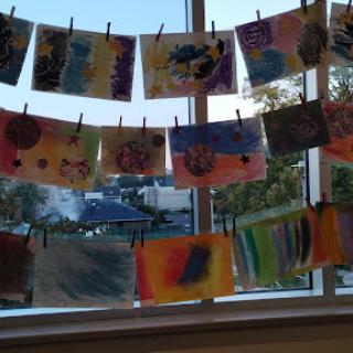 A vibrant display of children's artwork hanging by the window.