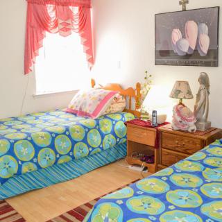 A cozy bedroom with twin beds featuring bright, colorful bedding and a warmly lit nightstand.