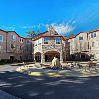 A large residential building with a stone facade and an inviting entrance under a clear blue sky.
