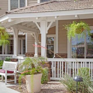 A cozy porch with a bench and potted plants, part of a charming house exterior.