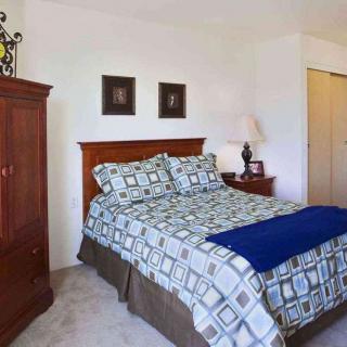 A cozy bedroom featuring a neatly made bed with patterned bedding, a wooden wardrobe, and decorative elements.