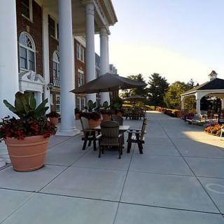 An elegant outdoor patio area with large columns, furniture, and potted plants.