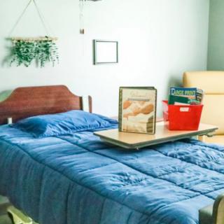 A cozy bedroom setup with blue bedding and a bed tray holding a book.