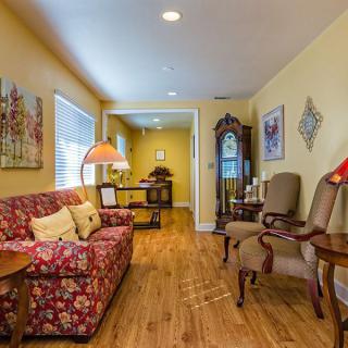 A traditional living room featuring a floral sofa, armchairs, and a grandfather clock.