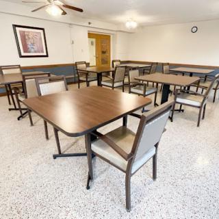 A spacious dining area featuring several tables and chairs, designed for communal gatherings.