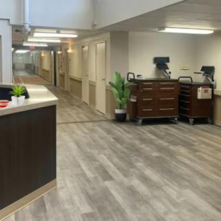 A hospital hallway featuring a reception desk and medical equipment carts.