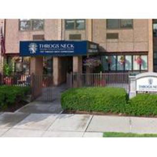 Entrance to Throgs Neck medical care facility with blue awning and landscaped surroundings.