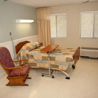 A hospital patient room featuring a bed, a chair, and a wheelchair.