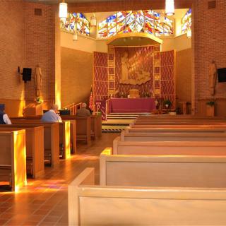 A serene church interior with wooden pews and a stained glass backdrop.