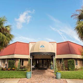 A welcoming entrance with palm trees and a clear blue sky.