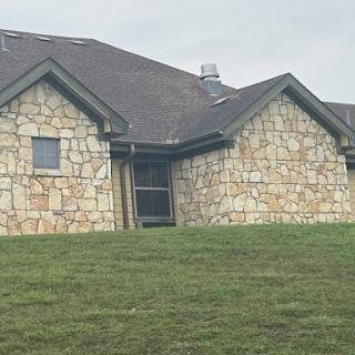 A charming stone house set against a grassy landscape.