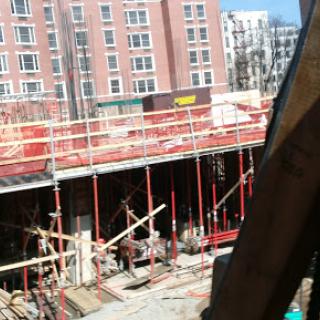 A view of an active construction site with scaffolding and workers in an urban environment.