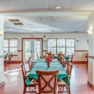 A well-lit dining area with neatly arranged tables and chairs, adorned with floral centerpieces.