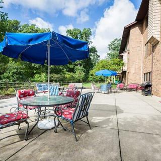 A patio area with outdoor furniture and umbrellas next to a brick building on a sunny day.