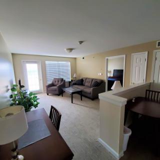 A cozy living room featuring comfortable sofas and chairs, a desk with a lamp, and decorative elements.
