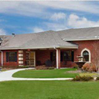 A brick residential house with a well-maintained lawn and clear sky.