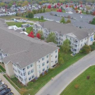 Aerial view of suburban apartment buildings surrounded by roads and trees.
