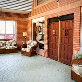A cozy porch area with wicker furniture and brick walls.