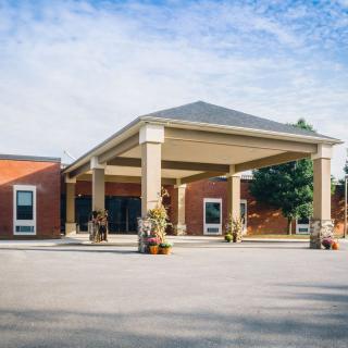 A brick building with a large entrance canopy and decorated with plants.