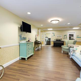 A cozy living room with wooden flooring, featuring comfortable seating and a mounted TV.