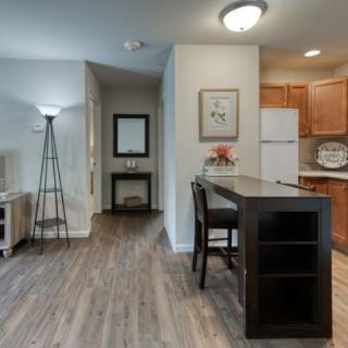 A modern interior featuring a kitchen with wooden cabinets and a dining area, complemented by stylish furniture and a floor lamp.