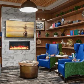 A modern and cozy living room with vibrant blue armchairs, a fireplace, and bookshelves.