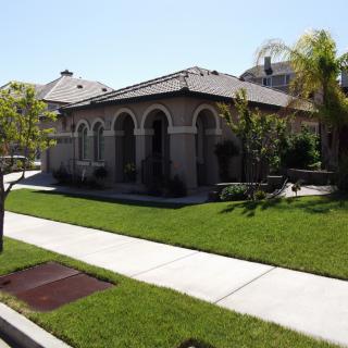 A suburban house with a well-maintained lawn and trees on a sunny day.