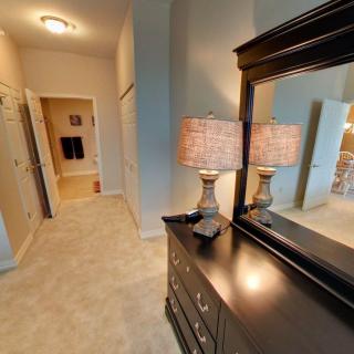 A hallway with a dresser and mirror, illuminated by a table lamp.