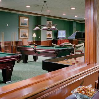 A cozy billiards room with multiple pool tables and comfortable seating.