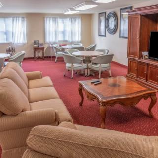 A cozy living room with sofas, a coffee table, and a television, complemented by several tables and chairs.