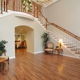 A spacious living area featuring a grand staircase and wooden flooring.