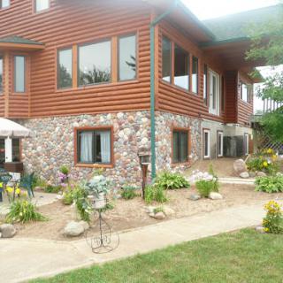 A beautifully designed house with a mix of wooden and stone exterior, surrounded by a well-maintained garden.