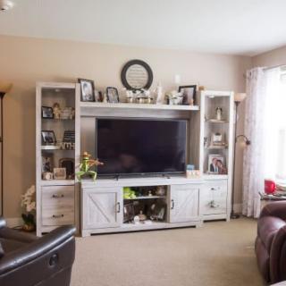 A cozy living room featuring a large entertainment center with a TV and decorative shelves.