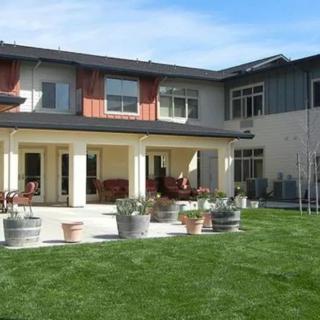 A two-story residential building with a well-maintained lawn and patio area.