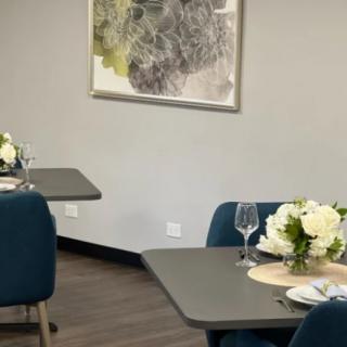 A modern dining room with neatly arranged tables, decorated with white flowers and elegant tableware.