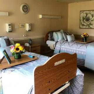A clean and organized hospital room with two patient beds, featuring a warm and welcoming decor.
