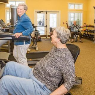 Seniors exercising in a gym with various fitness equipment.
