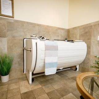 A serene bathroom featuring a vintage-style bathtub with towels draped over it, surrounded by tiled walls and decorative plants.