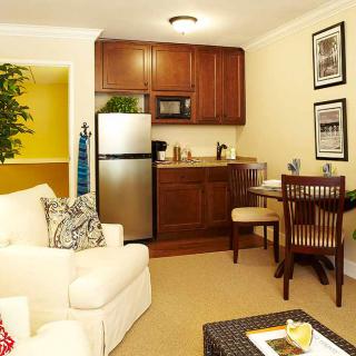A cozy living space featuring a compact kitchen with wooden cabinets and a small dining area.