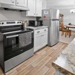 A modern kitchen with stainless steel appliances and a dining area in the background.
