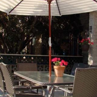 A serene outdoor patio with a table and chairs under a sun umbrella, adorned with a potted plant.